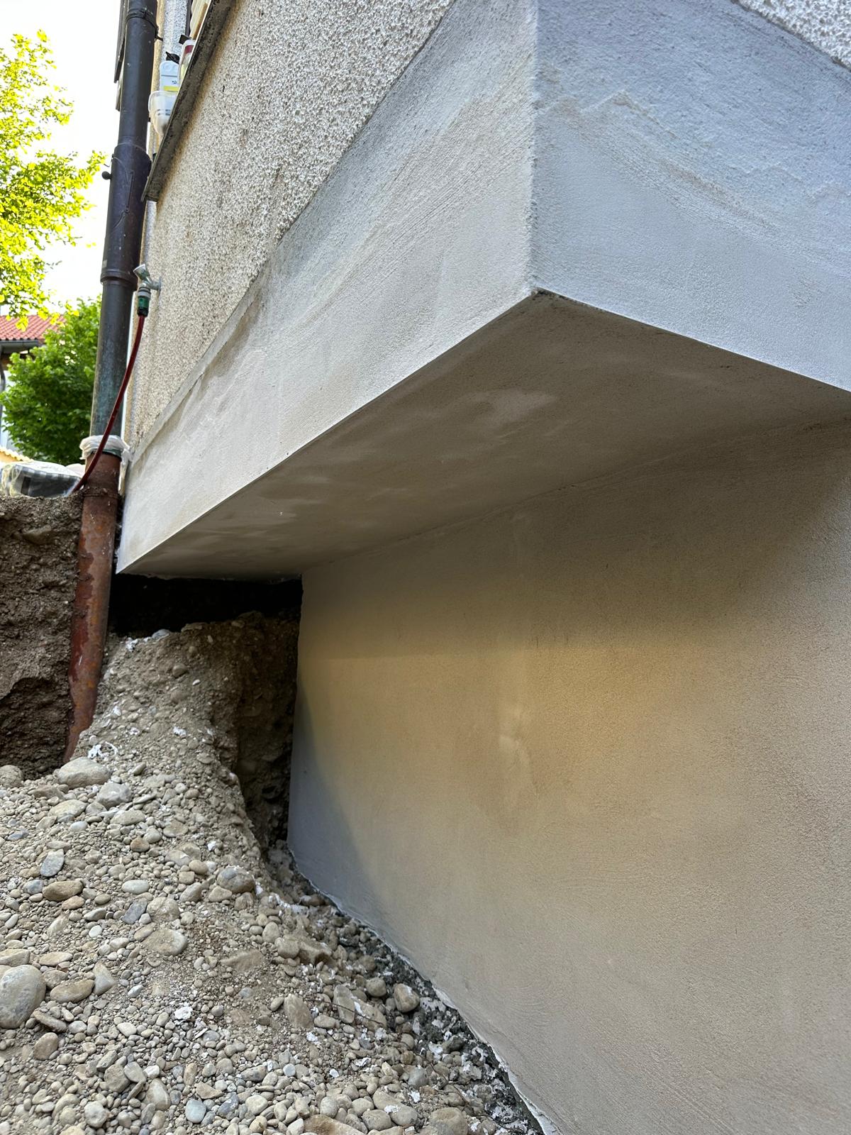 Sanierte Hauswand mit neu verputztem Sockelbereich – fachgerechte Putz- und Sanierungsarbeiten zur Abdichtung und Stabilisierung der Fassade im Fundamentbereich.